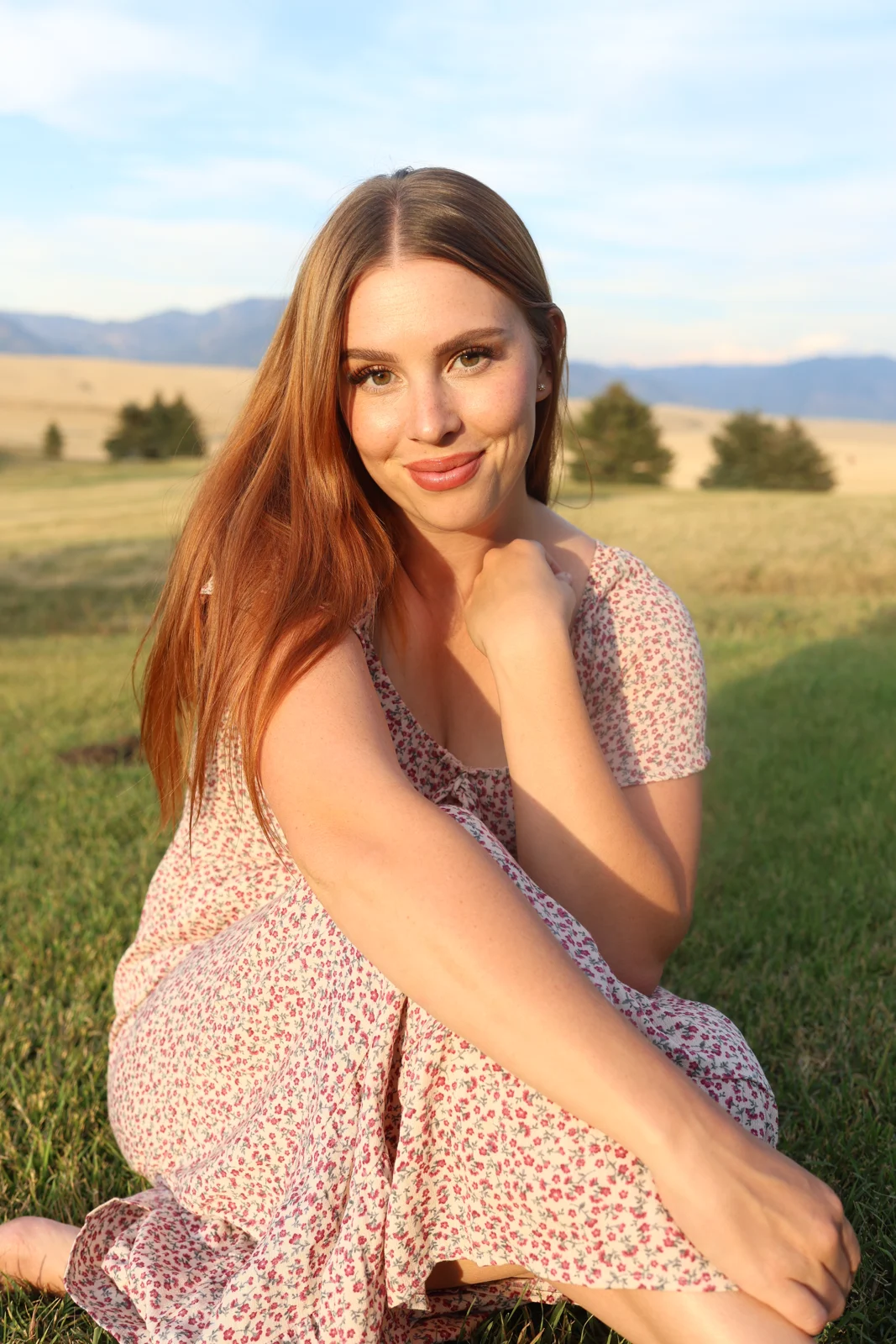 Megan, The Dandelion Doula, sitting in a sunlit meadow