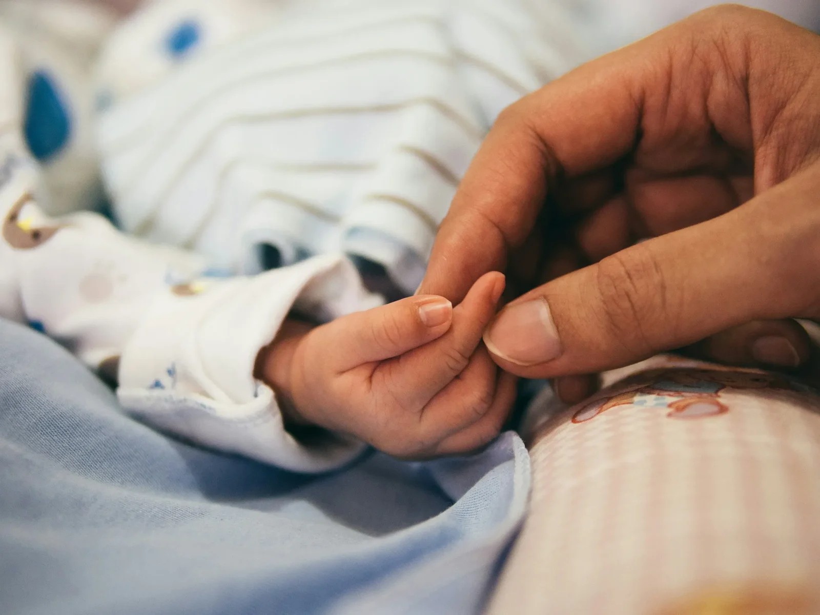 A newborn’s tiny hand resting in a parent’s hand